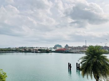 View of buildings at waterfront against cloudy sky