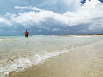 Man standing in sea against sky