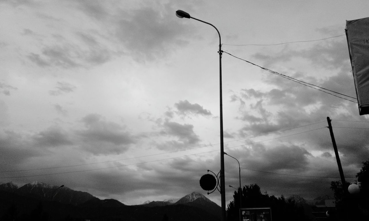 sky, silhouette, street light, low angle view, cloud - sky, cloud, built structure, building exterior, cloudy, architecture, power line, lighting equipment, transportation, cable, outdoors, nature, dusk, connection