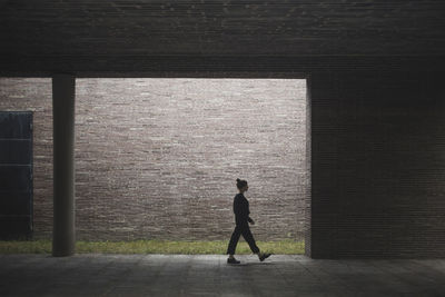 Side view of woman walking against wall