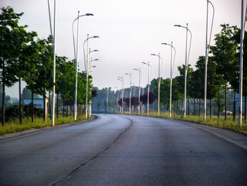 Empty road along street lights in city