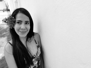 Portrait of a smiling young woman against wall