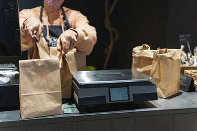 Female store owner keeping grocery bag by weight scale on counter