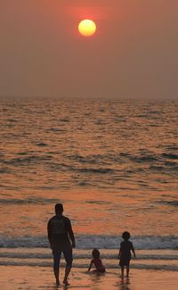 Silhouette people at beach against sky during sunset