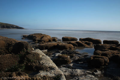 Rocks on beach against clear sky