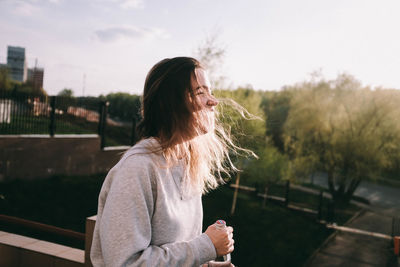 Woman standing by railing against sky