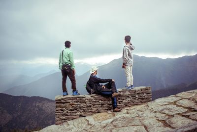 People sitting on mountain against sky