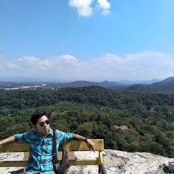 Young man wearing sunglasses sitting on mountain