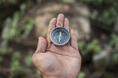 Close-up of woman holding navigational compass on field