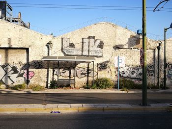 Graffiti on wall by road against buildings in city