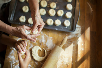 Cropped image of granddaughter and grandmother making cookies at kitchen counter