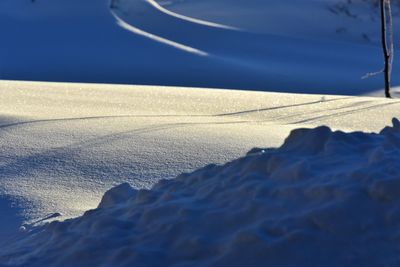 Surface level of snowy land against blue sky