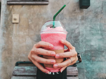 Midsection of man holding ice cream cone against wall