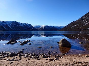 Scenic view of lake by mountains against sky