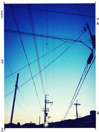 Low angle view of electricity pylon against blue sky