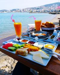 Close-up of breakfast served on table by sea against sky