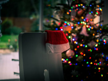 Close-up of santa hat against illuminated christmas tree at night