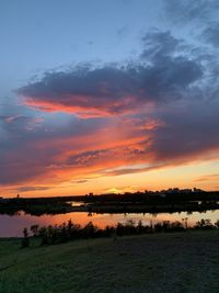 Scenic view of lake against dramatic sky during sunset