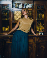 Young woman standing against cabinet at home