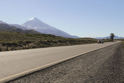 Road by mountains against clear blue sky