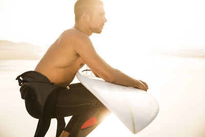 Side view of young man sitting on beach