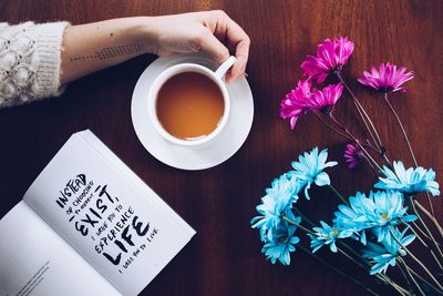 High angle view of hand holding coffee cup on table