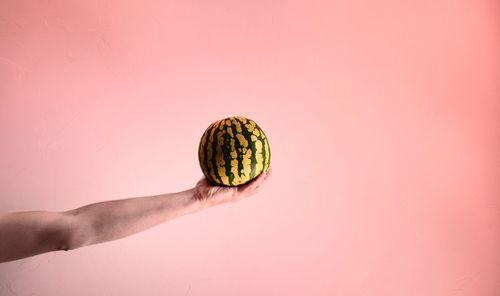 Close-up of hand holding drink against white background