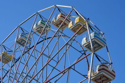 Low angle view of ferris wheel against clear blue sky