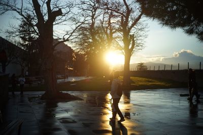 Silhouette people by swimming pool against sky during sunset