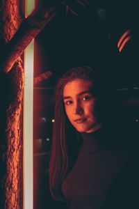 Portrait of young woman standing against wall