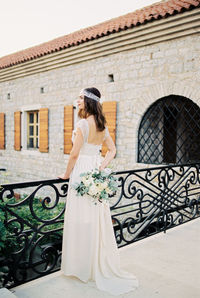 Side view of woman standing against building