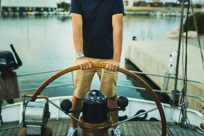 Low section of man holding steering wheel in boat
