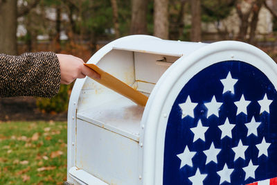 Close-up of hand putting mail in box