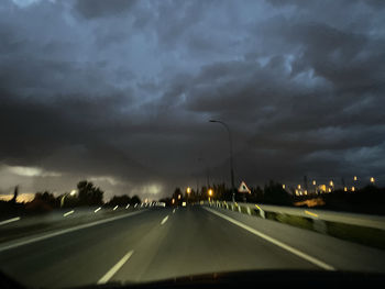 Cars on road against cloudy sky