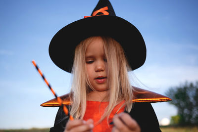 Close-up of girl wearing costume standing against sky