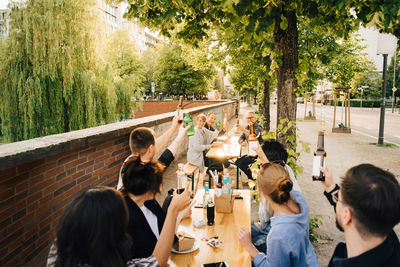 Male and female friends toasting while sitting at social gathering