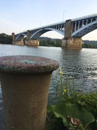 Arch bridge over river against sky in city