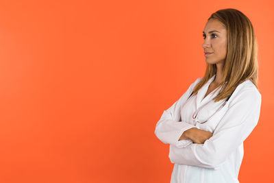 Portrait of young woman standing against yellow background