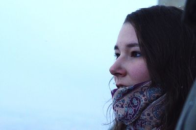 Portrait of young woman looking away against sky