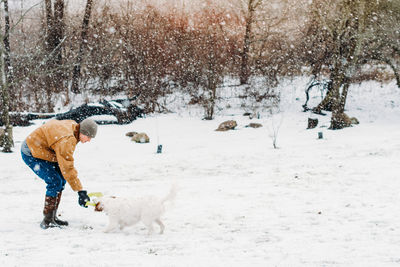 Rear view of man with dog on snow