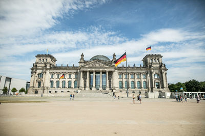 Tourists at historical building against cloudy sky