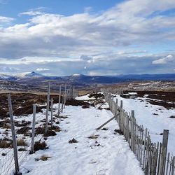 Snow covered landscape against cloudy sky