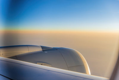 Close-up of airplane wing against sky during sunset