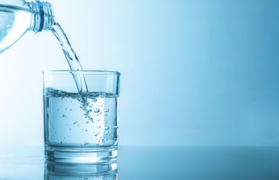 Close-up of glass of water against blue background