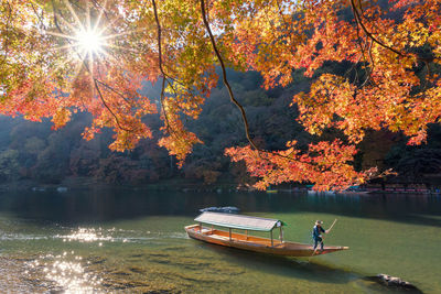 Man on boat in lake against sky during autumn