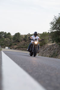 Man riding motorcycle on road against sky