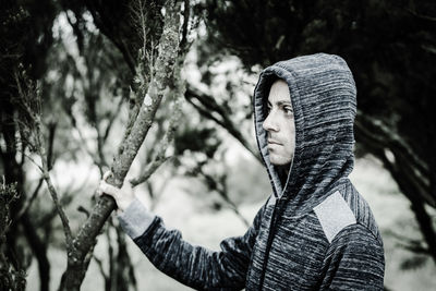 Close-up of man looking away while holding branch