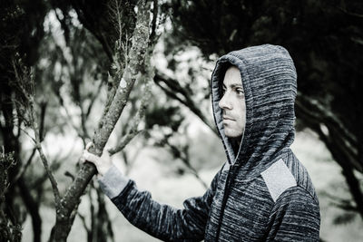 Close-up of young man against tree trunk