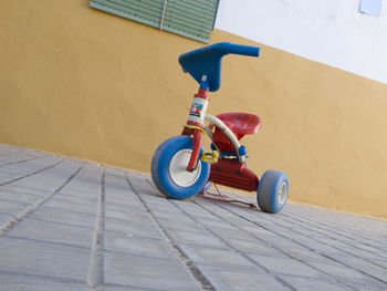 Toy bicycle on footpath against wall