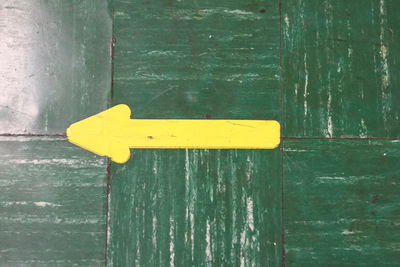 Close-up of arrow symbol on green door